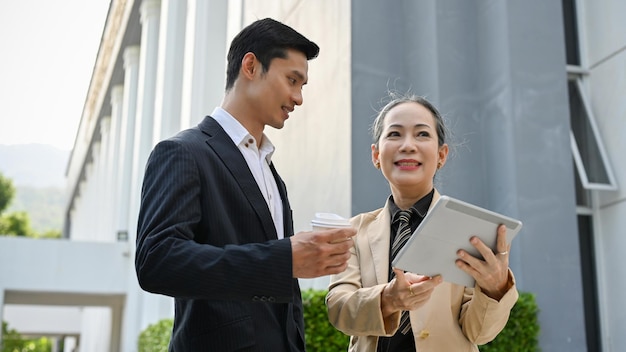 Asian male banker having a conversation with aged businesswoman outside the building