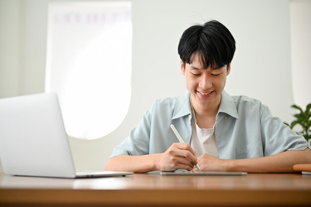 Asian male college student doing homework writing diary or taking notes on his school book