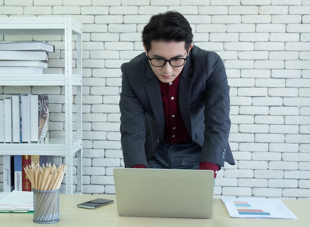 写真 アジアの男性会社員やオフィスの机に座っているビジネスマン