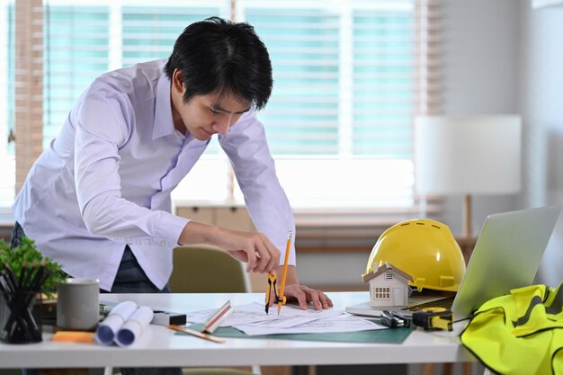 Asian male construction engineer working with blueprint in office