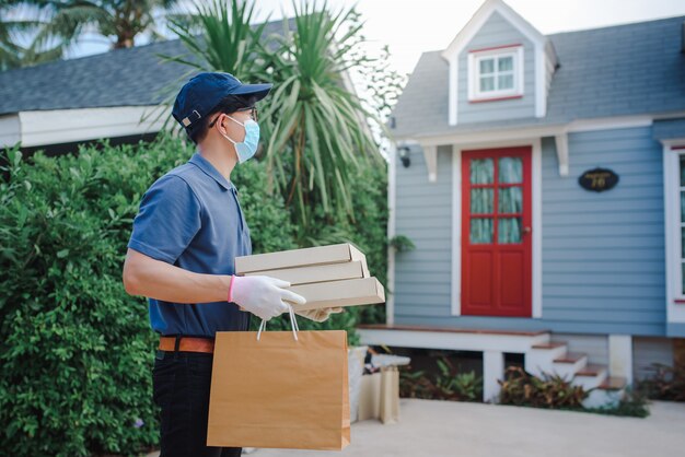 Asian male deliverers wear protective masks and medical gloves for online delivery. Home delivery service under quarantine conditions of Coronary Disease-19 virus outbreak