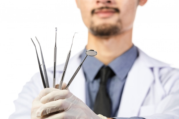 Asian male dentist with tools on white