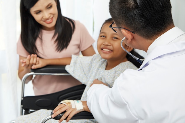 Asian male doctor talking to young child wheelchair and mother, Concept hospital care