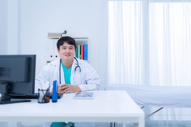 Азиатский врач-мужчина в белом халате в медицинском кабинете или клинике