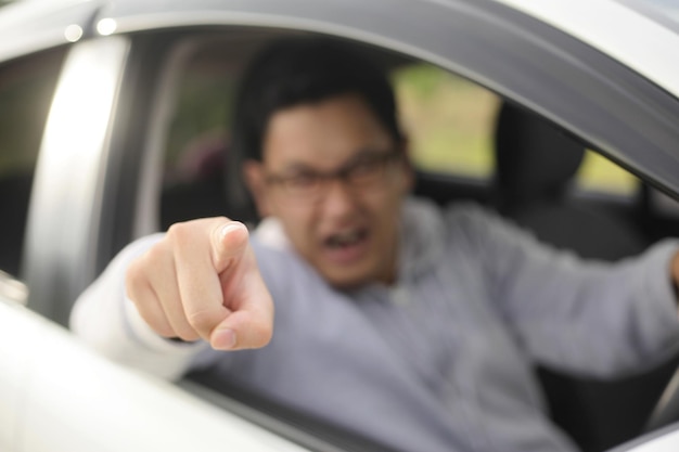 Photo asian male driver getting mad and angry from the traffic screaming and pointing from his car