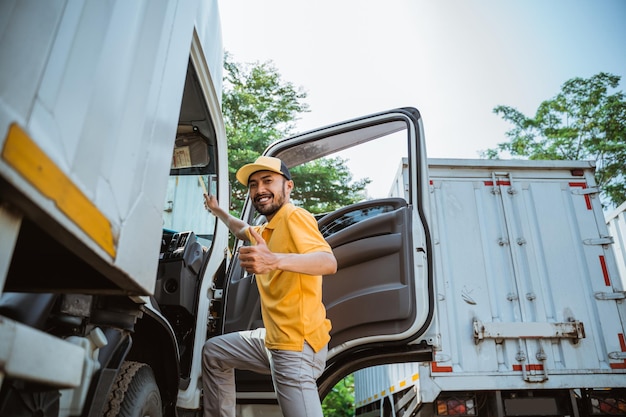 Asian male driver with thumbs up entering delivery truck