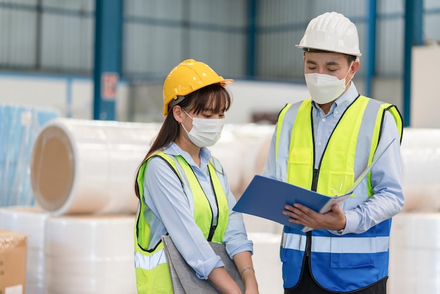 Asian male engineer hold documents explaining training with female technician at  warehouse factory