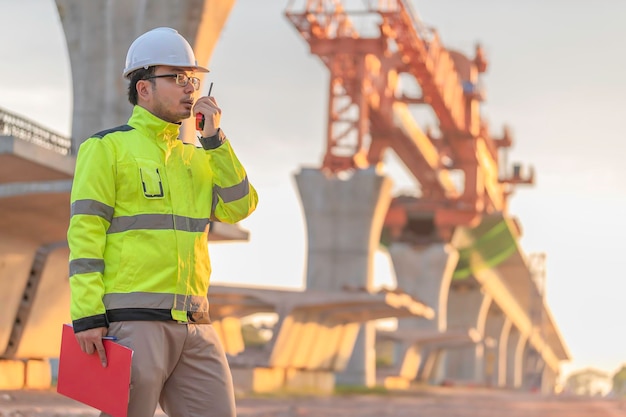 An Asian male engineer works at a motorway bridge construction siteCivil worker inspecting work on crossing constructionSupervisor working at highspeed railway construction site