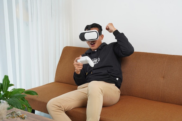 asian male enjoy metaverse gaming with vr headset playing virtual gaming sport in the living room