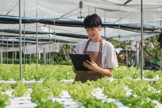 写真 アジアの男性農家が水耕野菜を育てる 農家が健康のためにレタスを栽培する ビジネスオーナー グリーンハウス栽培 健康食品についての環境起業家