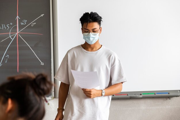 Asian male high school student wearing protective face mask gives a presentation Copy space