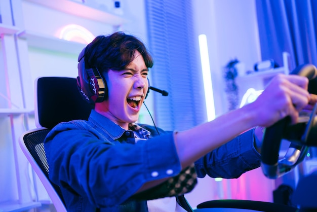 Asian male pro gamer playing an online car drive simulation game with steering wheel controller Gamer winning an esports game with victory emotion The player rejoices in victory in the competition