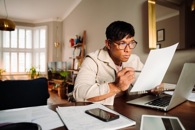 Asian male reading document while working from home