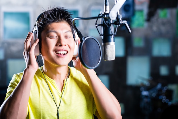 Asian male singer producing song in recording studio