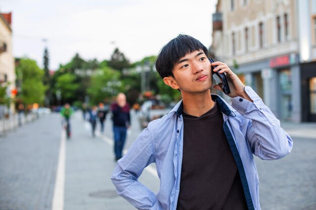 asian male student tourist talking on phone outdoors