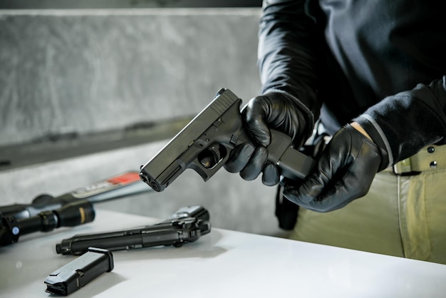 Foto maschio asiatico che indossa guanti di pelle nera con la pistola nel caricamento manuale dei proiettili alla pistola