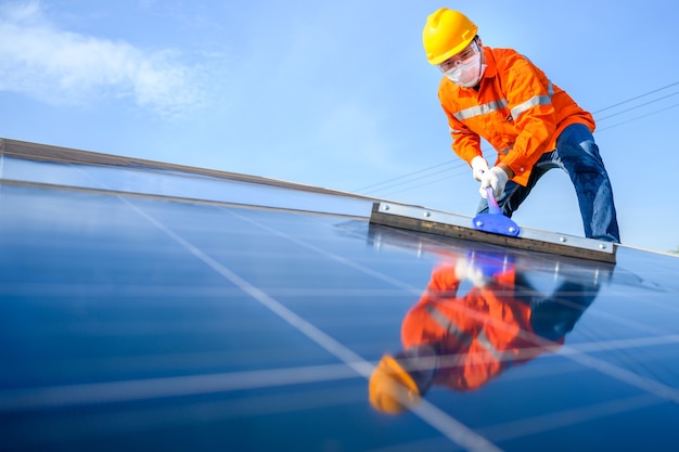 Asian male worker or engineer In a solar power station The solar panel is being cleaned using a mop to clean it. At the solar power station.