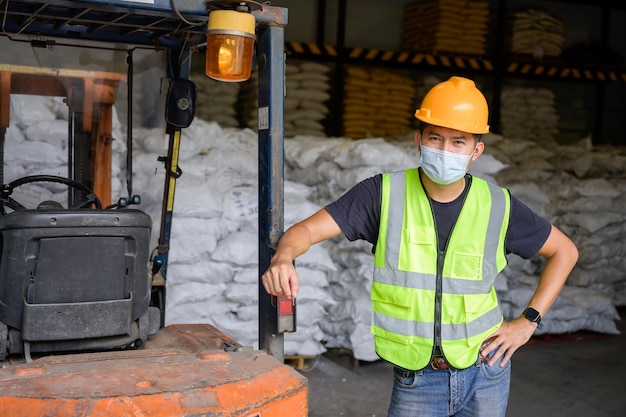 Asian male worker Work in a chemical industry Young Asian man wearing an orange helmet Driving forklifts in industrial warehouses The background is a warehouse and goods