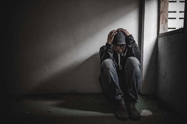 Asian man addict drug in the deserted placeA junkie feels alone in this worldSad young man sitting in the corner of the roomPeople are stressed and have depression