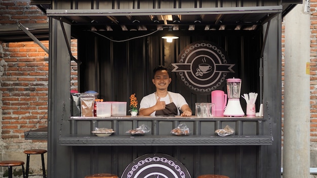 Asian man in apron guarding container angkringan gesturing okay