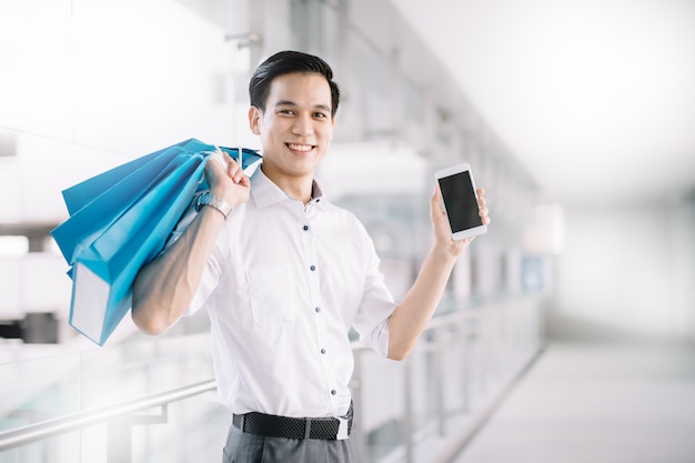 Asian man are shopper holding smart phone and shopping bag in shopping mall