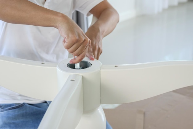 Asian man assembling white table furniture at home