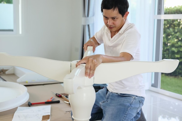 Asian man assembling white table furniture at home