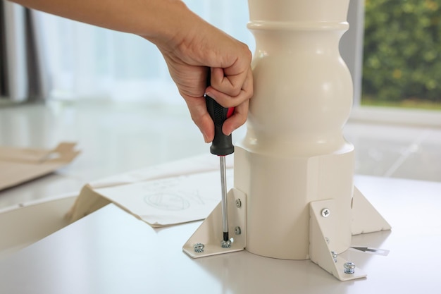 Asian man assembling white table furniture at home