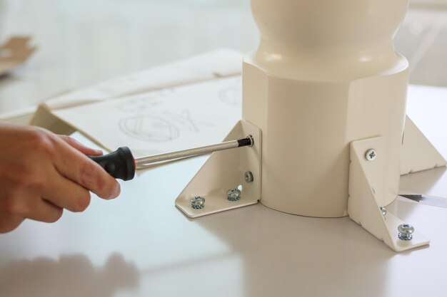 Asian man assembling white table furniture at home