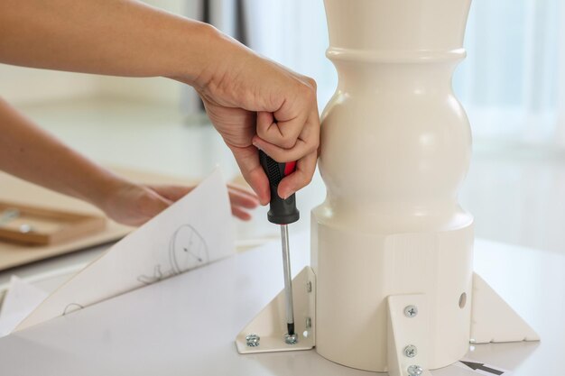 Asian man assembling white table furniture at home