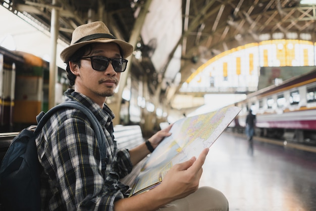 タイの鉄道駅の地図でアジア人の袋パックの観光客。