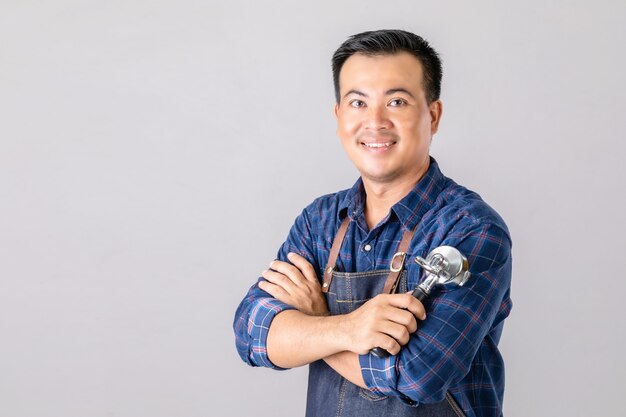 Asian man in barista uniform holding coffee machine tool