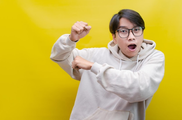 asian man in beige hoodie dancing happily and raising his fist celebrating victory