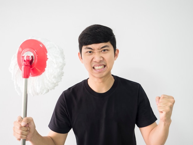 Foto la camicia nera dell'uomo asiatico si sente arrabbiato con il pugno alzato tenendo in mano il mocio su sfondo bianco isolato