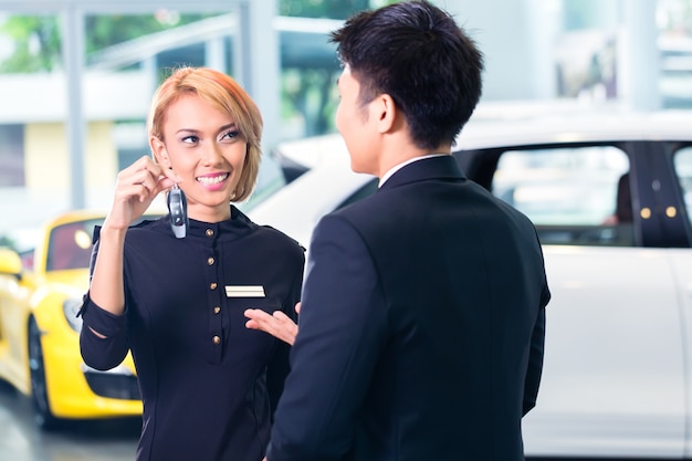 Asian man at car rental receiving key