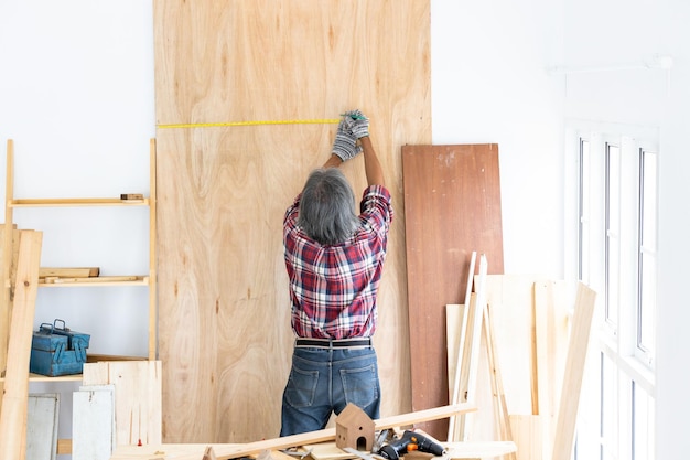 Asian man carpenter working on woodworking in carpentry shop Carpenter working on wood craft at workshop construction material wooden furniture Asian man works in a carpentry shop