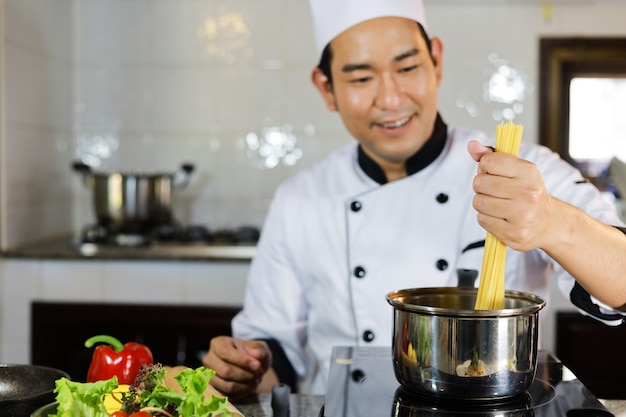 Cuoco unico asiatico dell'uomo che cucina alimento in ristorante