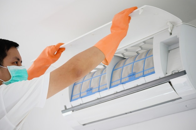 Asian man cleaning air conditioner dirty filter