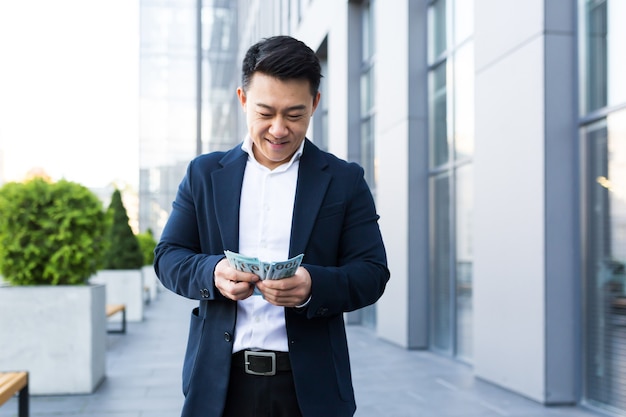 Asian man counts money near the office, happy businessman got a lot of cash