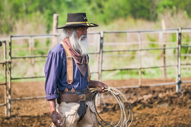 Asian Man Cowboy is een kalf aan het vangen Om in een ranch te worden gebrandmerkt