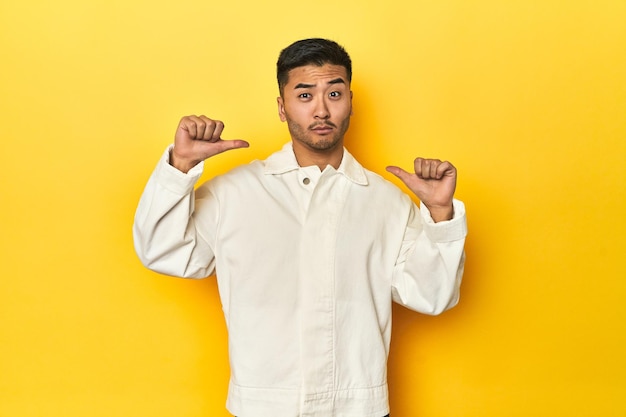 Foto un uomo asiatico in camicia bianca su uno studio giallo si sente orgoglioso e sicuro di sé, un esempio da seguire.