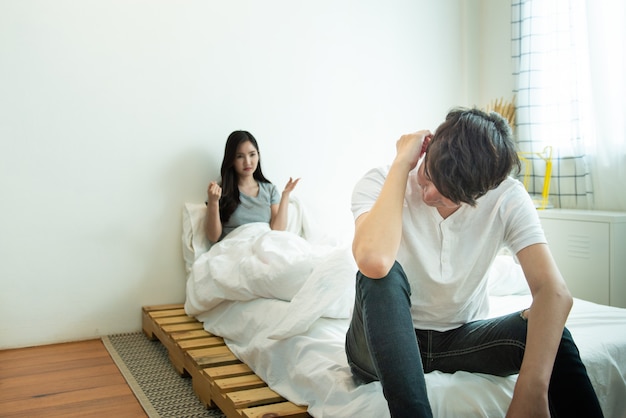 Asian man depresses and woman with unhappy relationship sit on bed after have an argument,social problem in couple live.