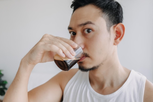 アジア人男性は、新鮮な朝のために彼の家でエスプレッソ コーヒーのショットを飲む