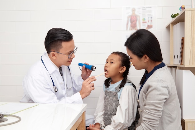 Фото Азиатский врач-мужчина разговаривает с малышами и матерью концепции профилактики и здравоохранения