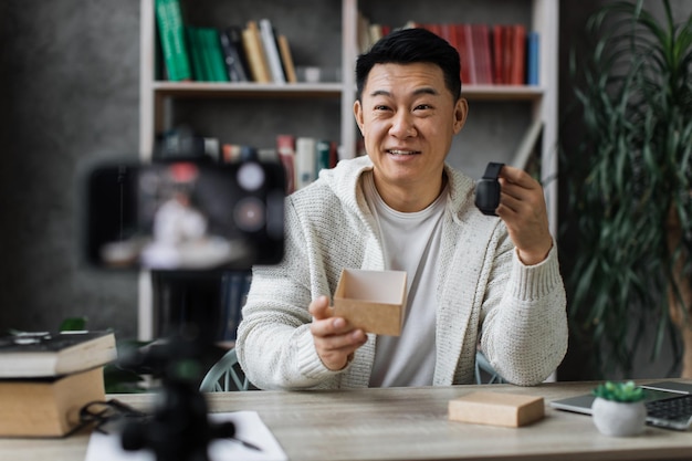 Asian man doing live stream while unpacking box with new smart watch