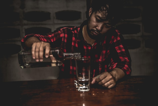 Asian man drink vodka alone at home on night timeThailand peopleStress man drunk concept