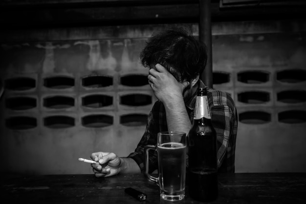 Asian man drinking beer and smoking alone at home on night timeThailand peopleStress man drunk concept