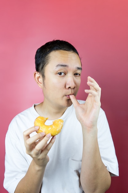 Photo asian man eating a delicious donut