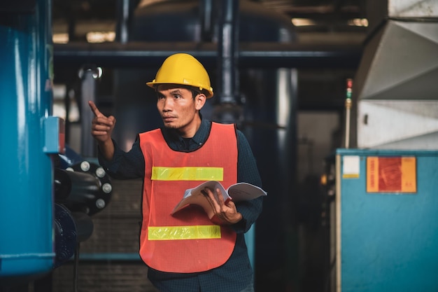 L'ingegnere asiatico sta lavorando in fabbrica e controllando il controllo del sistema di sicurezza sulla produzione industriale