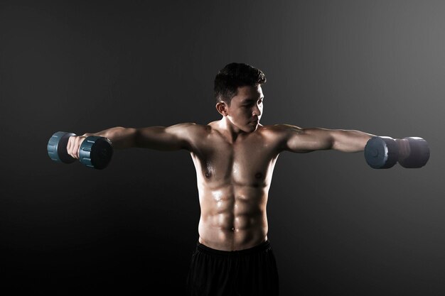 Asian man exercising his biceps with dumbbells